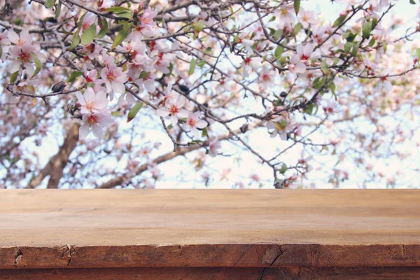 Table rustique en bois devant un arbre en fleurs de cerisier de printemps. affichage du produit et concept de pique-nique . — Photo