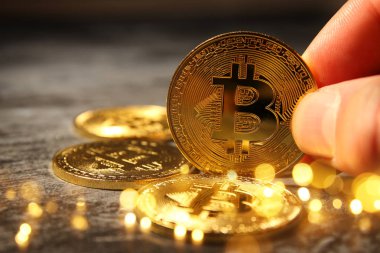 Altın Bitcoin siyah arka plan üzerinde tutan adam. İş kavramı.