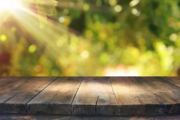 Imagen de mesa de madera frente a un paisaje de viñedo borroso a la luz del sol. Listo para montaje en pantalla de producto . — Foto de Stock