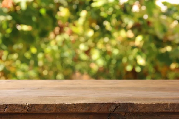 Obrázek dřevěný stůl před rozmazané vinice krajinu na sluneční světlo. Připravena k montáži zobrazení produktu. — Stock fotografie