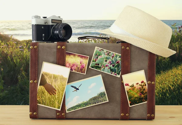 Зображення старовинного старовинного багажу, капелюха і старовинної фотоапарата з фотографіями природи над дерев'яною підлогою . — стокове фото