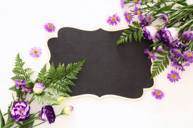 En iyi görünümü boş yazı tahtası Beyaz ahşap zemin üzerinde ve mor güzel çiçek aranjman. Kopya alanı.