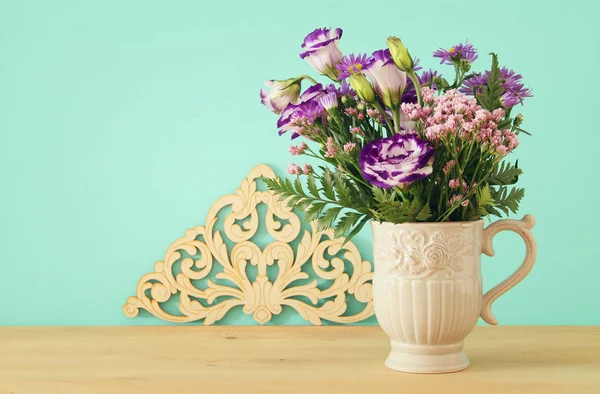 Летний букет фиолетовых цветов в вазе на деревянном столе и мятном фоне . — стоковое фото