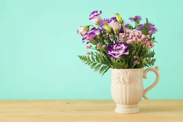 Bouquet d'été de fleurs violettes dans le vase sur table en bois et fond menthe . — Photo