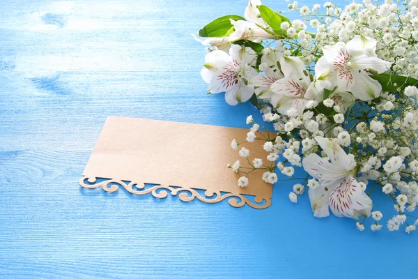 Вид сверху на расположение белых красивых цветов и пустую букву на голубом деревянном фоне. Копирование пространства . — стоковое фото