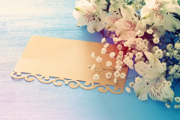 Vista superior do arranjo de flores bonitas brancas e carta vazia sobre fundo de madeira azul. Espaço de cópia . — Fotografia de Stock