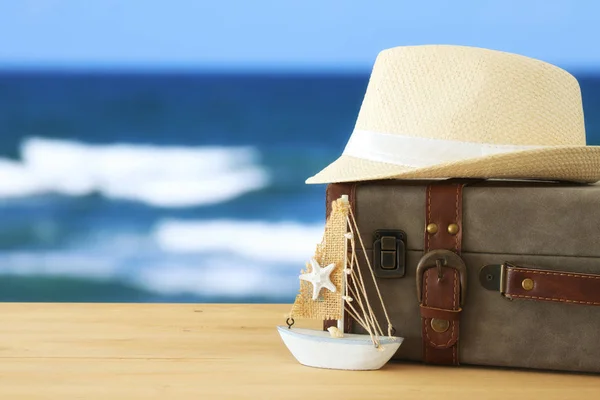 海風景の infront の木製テーブルの上ヴィンテージ荷物、ボートおよび fedora 帽子を旅行。休日と休暇の概念. — ストック写真