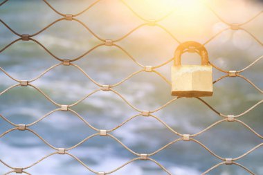 Mavi deniz arka plan ile demir çit üzerinden eski paslı kilit.