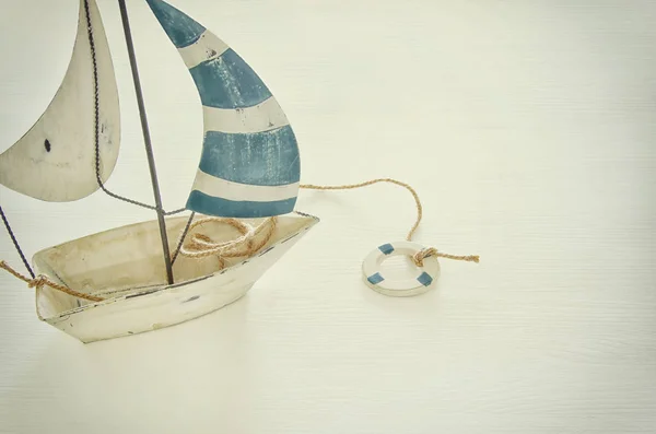 Concetto nautico con barca a vela decorativa bianca su tavolo di legno bianco. Immagine filtrata vintage . — Foto Stock