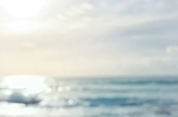 ボケ夕日の光でぼやけたビーチと海の波の背景. — ストック写真