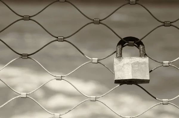 Gamla rostiga lock över järnstaket med havet bakgrund. Sepia filter. — Stockfoto