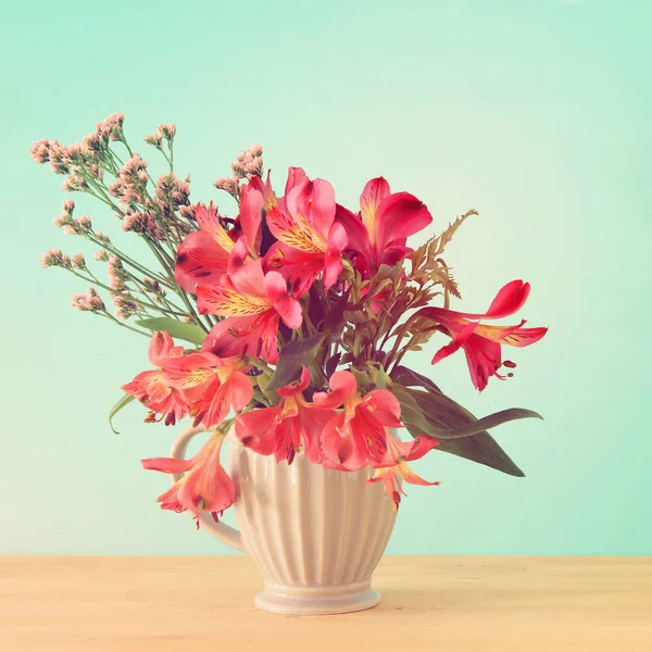 Ramo de verano de flores rojas en el jarrón sobre tabla de madera y fondo de menta . — Foto de Stock