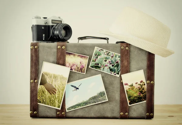 Зображення старовинного старовинного багажу, капелюха і старовинної фотоапарата з фотографіями природи над дерев'яною підлогою . — стокове фото