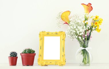 Güzel buket sarı bahar yanındaki boş vintage fotoğraf çerçevesinin üzerine beyaz masa görüntüsü. Fotoğraf montaj kadar sahte.