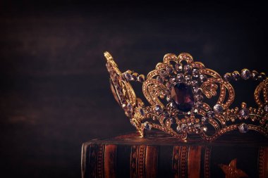 Tahta masanın üzerindeki güzel kraliçe ve kral tacının gösterişsiz görüntüsü. Eski model filtrelenmiş. fantezi ortaçağ dönemi.