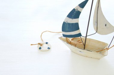 Beyaz ahşap masa üzerinde beyaz dekoratif yelkenli tekne ile deniz kavramı.