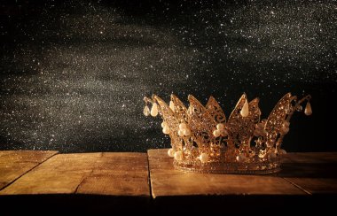Tahta masanın üzerindeki güzel kraliçe ve kral tacının gösterişsiz görüntüsü. Eski model filtrelenmiş. fantezi ortaçağ dönemi.