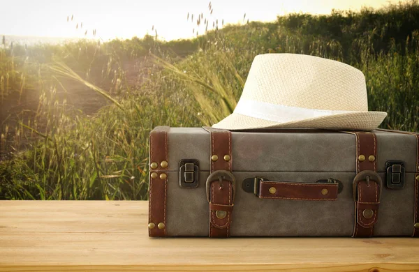 Reiziger vintage bagage en fedora hoed over houten tafel. vakantie en vakantie concept. — Stockfoto