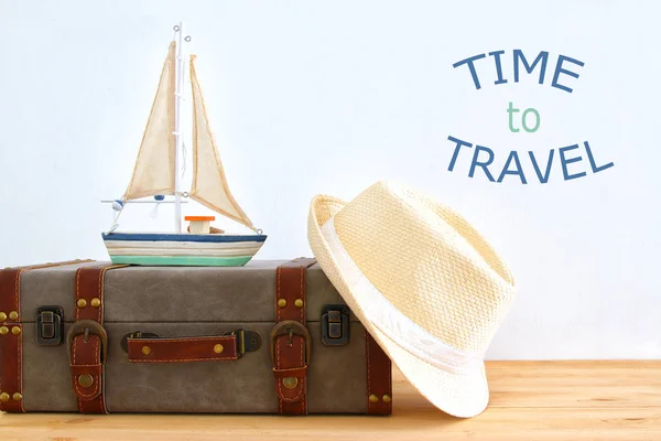 Viaggiatore vintage bagaglio, barca e cappello fedora sopra tavolo in legno. vacanza e concetto di vacanza . — Foto Stock