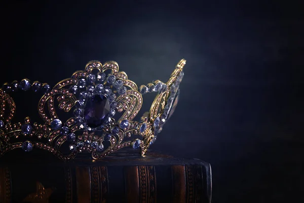 Tahta masanın üzerindeki güzel kraliçe ve kral tacının gösterişsiz görüntüsü. Eski model filtrelenmiş. fantezi ortaçağ dönemi. — Stok fotoğraf
