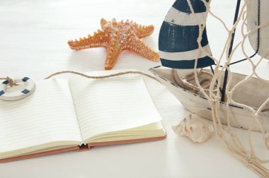 Deniz kavramı görüntü beyaz dekoratif yelkenli tekne ve Beyaz ahşap masa üzerinde boş açık Not Defteri ile.