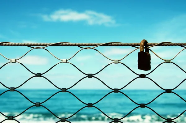 Régi rozsdás lakat, vas kerítés háttér kék tenger. — Stock Fotó