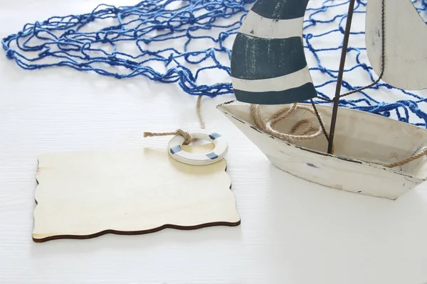 Concepto náutico imagen con velero decorativo blanco y tablero de madera vacío sobre mesa blanca . — Foto de Stock