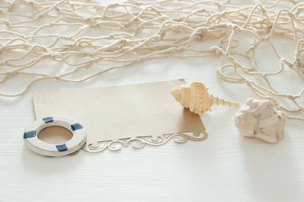 Tengeri koncepció kép a tengeri kagylókból, hal nettó és üres Megjegyzés fölött fehér fa asztal. — Stock Fotó