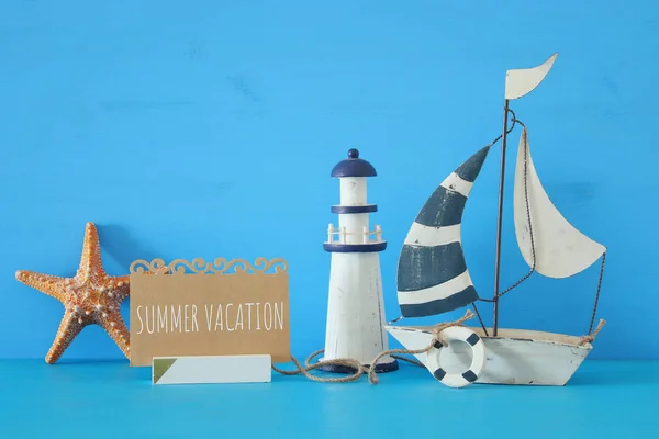 Nautiska konceptet bild med segelbåt, fyr, sjöstjärnor och observera över Blå träbord och bakgrund. — Stockfoto