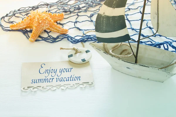 Nautiska konceptet bild med vita dekorativa segelbåt, sjöstjärnor och observera över vitt trä bord. — Stockfoto