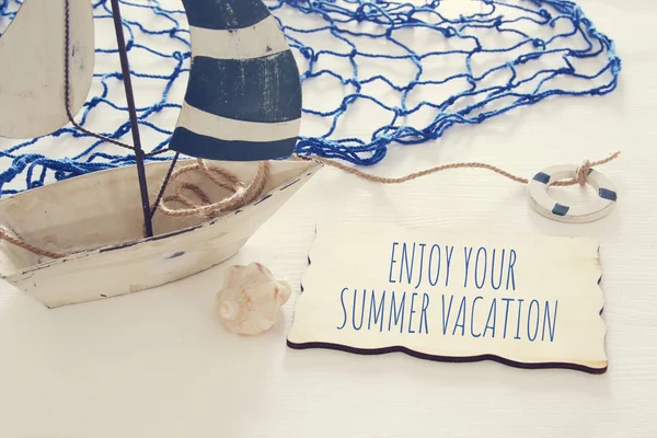 Deniz kavramı görüntü beyaz dekoratif yelkenli tekne ve ahşap tahta üzerinde metin ile: Enjoy Your yaz tatili. — Stok fotoğraf