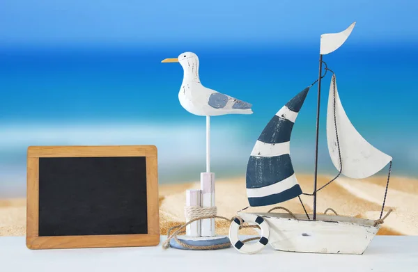 Concepto náutico con pájaro gaviota decorativo blanco, pizarra y barco sobre fondo de paisaje marino tropical . — Foto de Stock