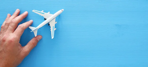 Adamın elinde oyuncak uçak mavi ahşap arka plan üzerinde tutarak fotoğrafı Üstten Görünüm. — Stok fotoğraf