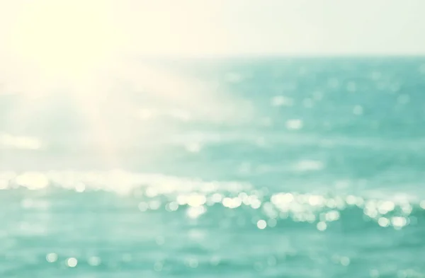 ボケ夕日の光でぼやけたビーチと海の波の背景. — ストック写真