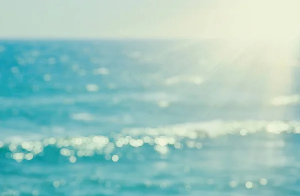 Fundo de praia turva e ondas do mar com luz bokeh por do sol . — Fotografia de Stock