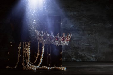 Image of mysterious opened old wooden treasure chest with light and queen/king crown with red Rubies stones. fantasy medieval period. Selective focus clipart