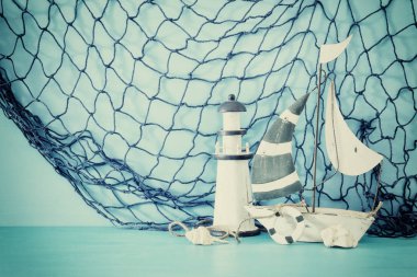 Beyaz dekoratif yelkenli tekne, deniz feneri, kabukları ve File mavi ahşap masa ve arka plan üzerinde deniz kavramı.