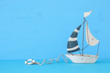 Mavi ahşap masa ve arka plan üzerinde beyaz dekoratif yelkenli tekne ile deniz kavramı.