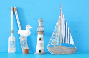 Beyaz dekoratif martı kuşu, lighthous, ahşap kürek ve tekne kürek üzerinde mavi arka plan ile deniz kavramı.