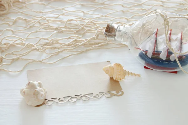 Image concept nautique avec voilier en bouteille et note vide sur table en bois blanc . — Photo