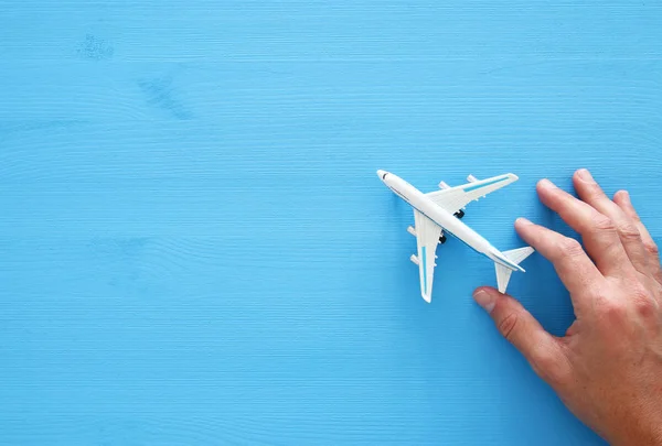 Adamın elinde oyuncak uçak mavi ahşap arka plan üzerinde tutarak fotoğrafı Üstten Görünüm. — Stok fotoğraf