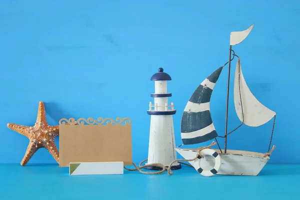 Nautiska konceptet bild med segelbåt, fyr, sjöstjärnor och Tom anteckning över Blå träbord och bakgrund. — Stockfoto