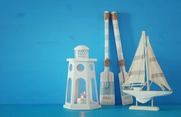Nautisches Konzept mit weißer dekorativer Leuchtturmlaterne, Holzrudern und Boot vor blauem Hintergrund. — Stockfoto