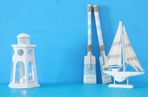 Concetto nautico con lanterna bianca decorativa faro, remi in legno e barca su sfondo blu . — Foto Stock