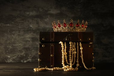 Gizemli açılan eski ahşap hazine sandığı ışık ve Kraliçe/kral taç kırmızı yakut ile görüntüsünü taşlar. fantezi Ortaçağ dönemi. Seçici odak