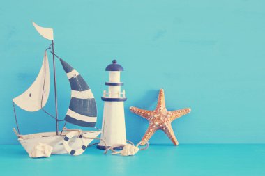 Beyaz dekoratif yelkenli tekne, deniz feneri, deniz yıldızı, deniz kabuklarını yere mavi ahşap masa ve arka plan ile deniz kavramı.