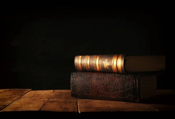 Imagen de pila de libros antiguos sobre mesa de madera y fondo oscuro . —  Fotos de Stock