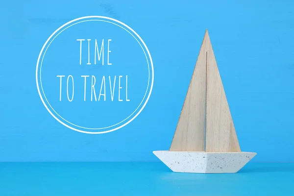 Concetto nautico con barca a vela decorativa bianca su tavola di legno blu e testo: tempo per viaggiare . — Foto Stock