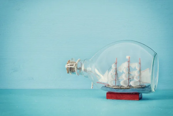 Imagem conceito náutico com barco à vela na garrafa sobre mesa de madeira azul e fundo. Foco seletivo . — Fotografia de Stock