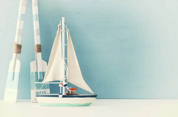 Морська концепція з білим декоративним вітрильним човном та дерев'яними веслами на синьому фоні . — стокове фото